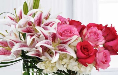 fragrant bouquet of pink & red roses, white hydrangea and Stargazer lilies with clear gemstones in the bottom of the vase.